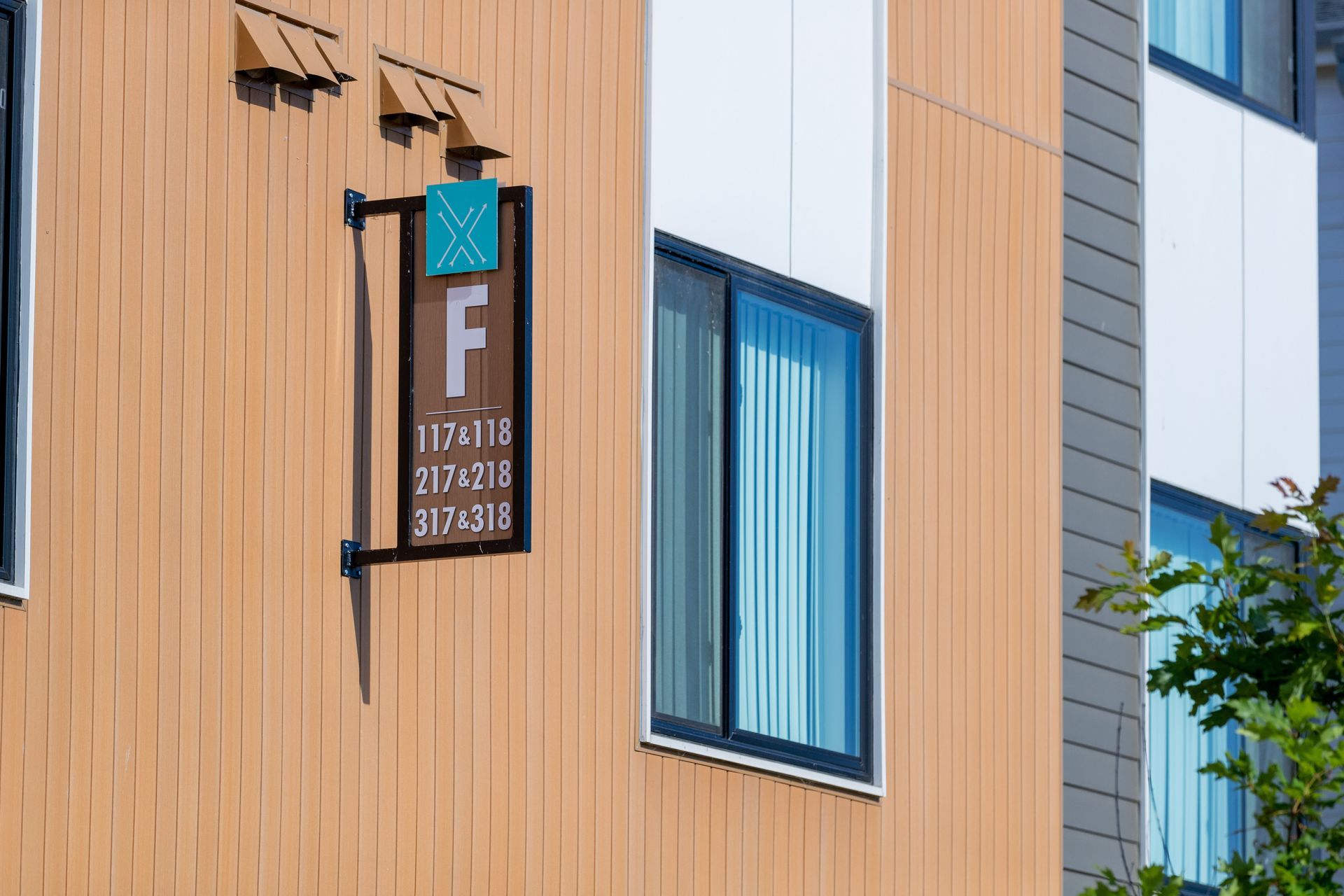 Wooden building facade with a hanging sign marked “F” beside blue-trimmed windows