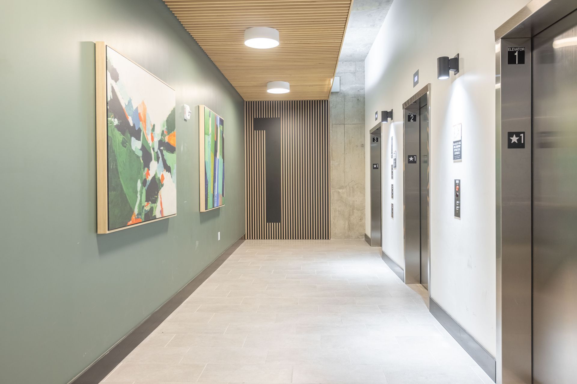 Modern hallway with elevators, wall art, and bright ceiling lights