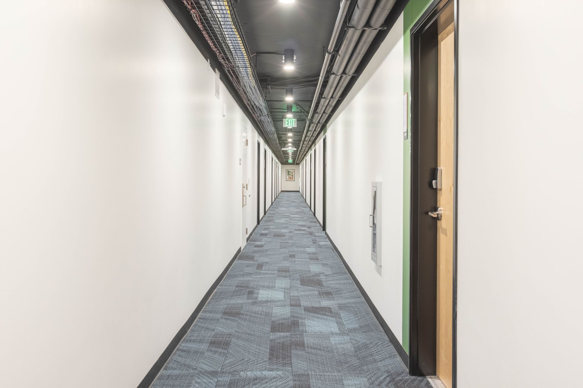 Long white office hallway with blue carpet and doors on both sides