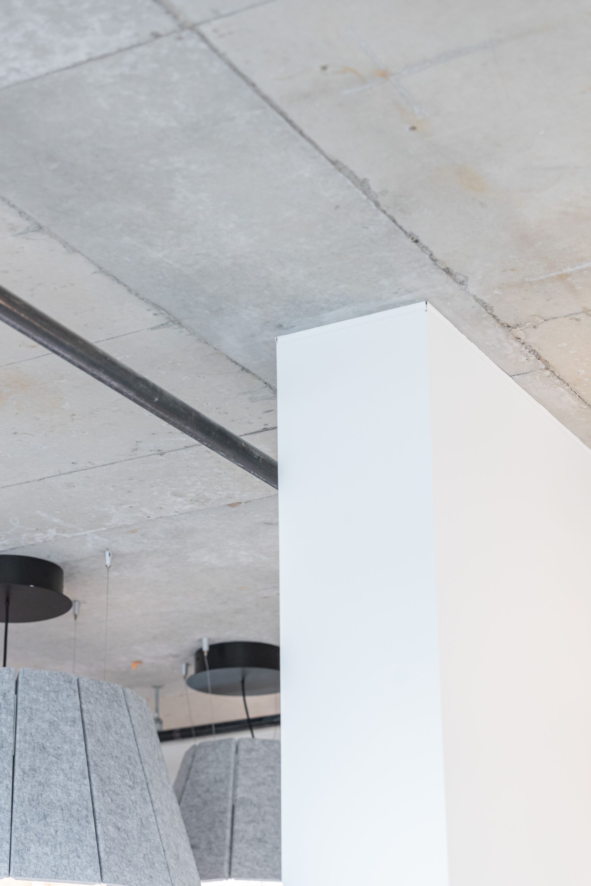 White column in a modern interior with concrete ceiling and hanging black lights