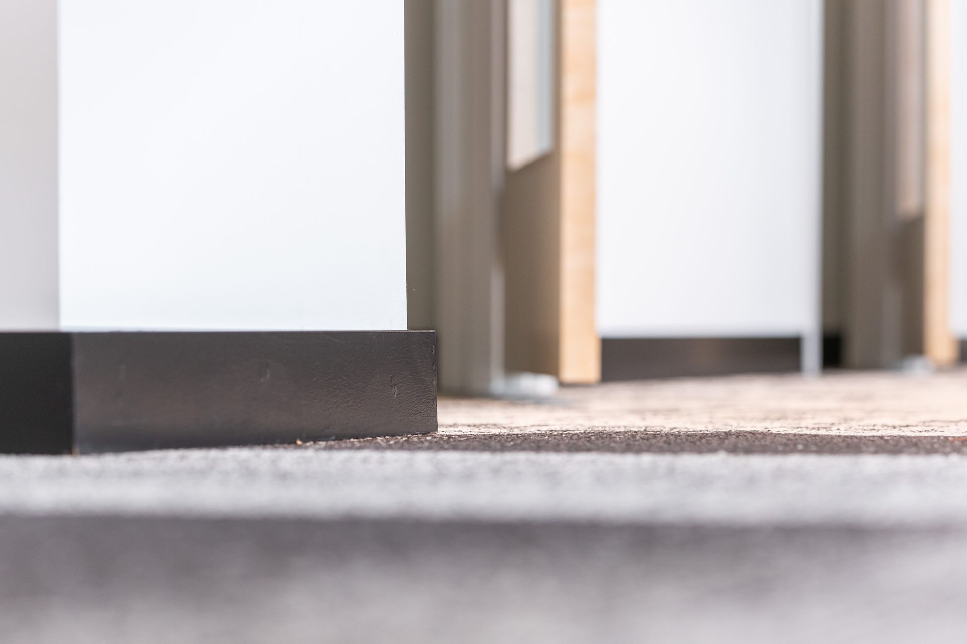 Close-up of a doorway threshold with beige pillars and a blurred gray floor