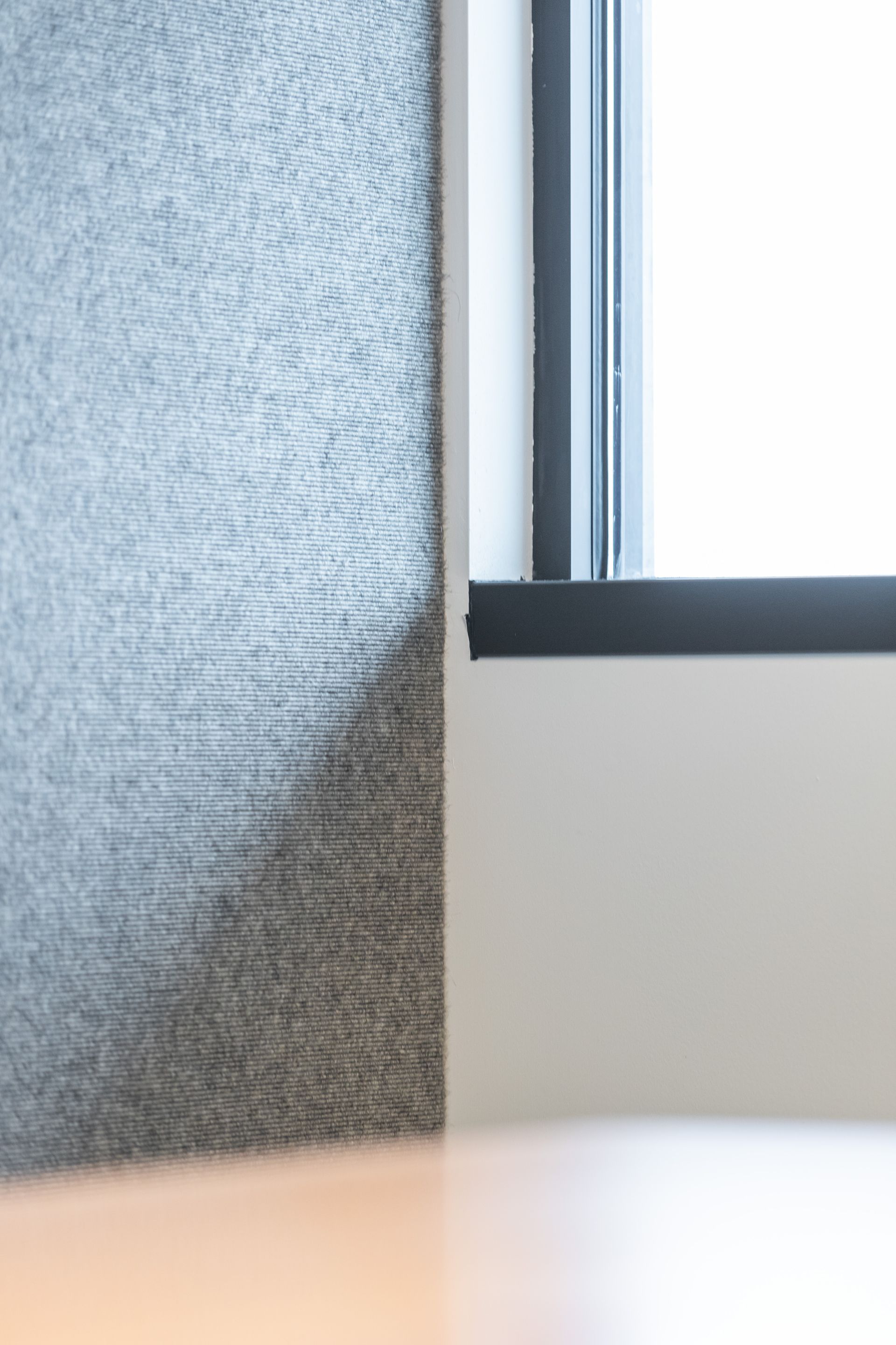 Close-up of a gray textured chair beside a window with white light and a blurred tabletop