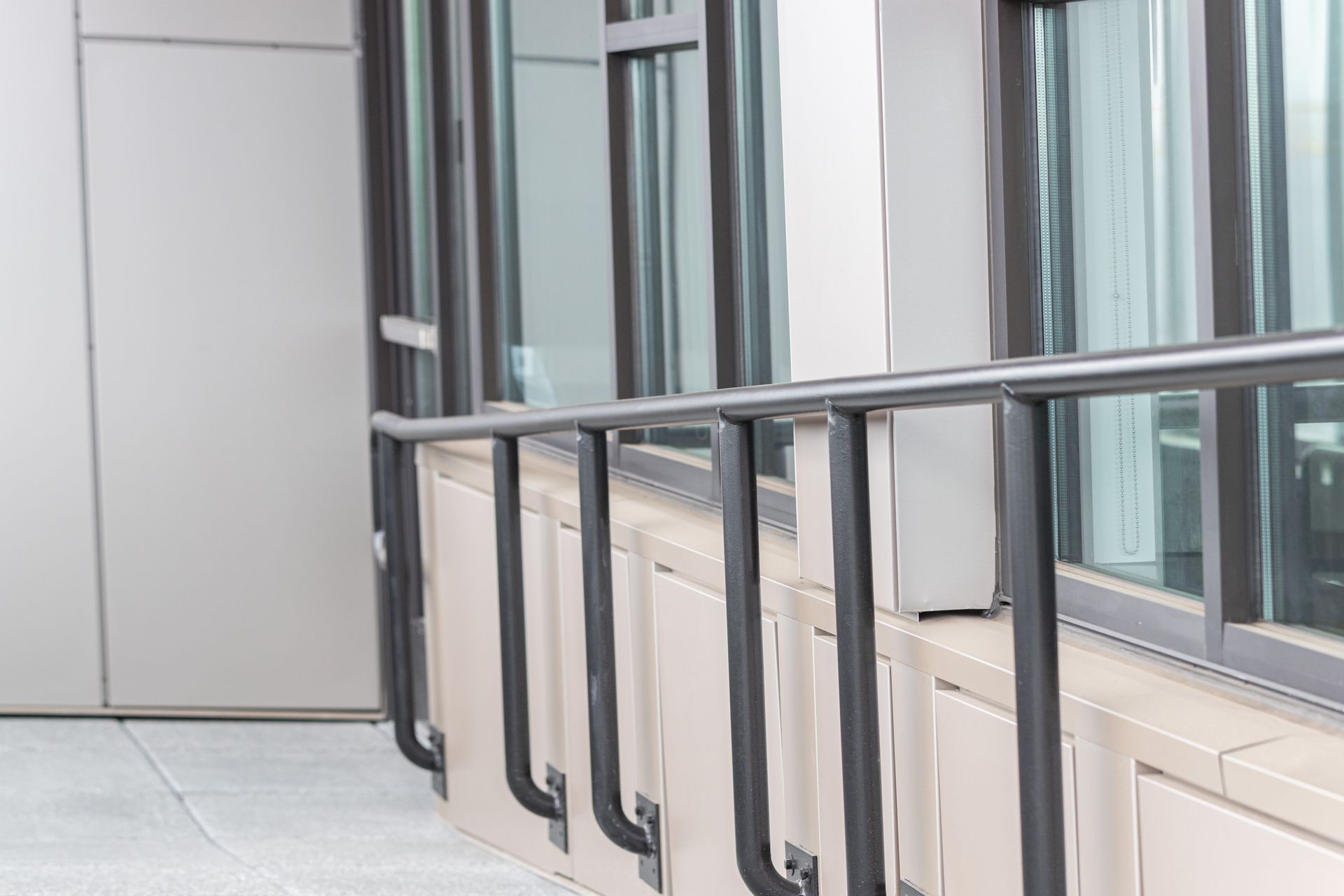 Indoor corridor with windows, metal railing, and a closed gray door