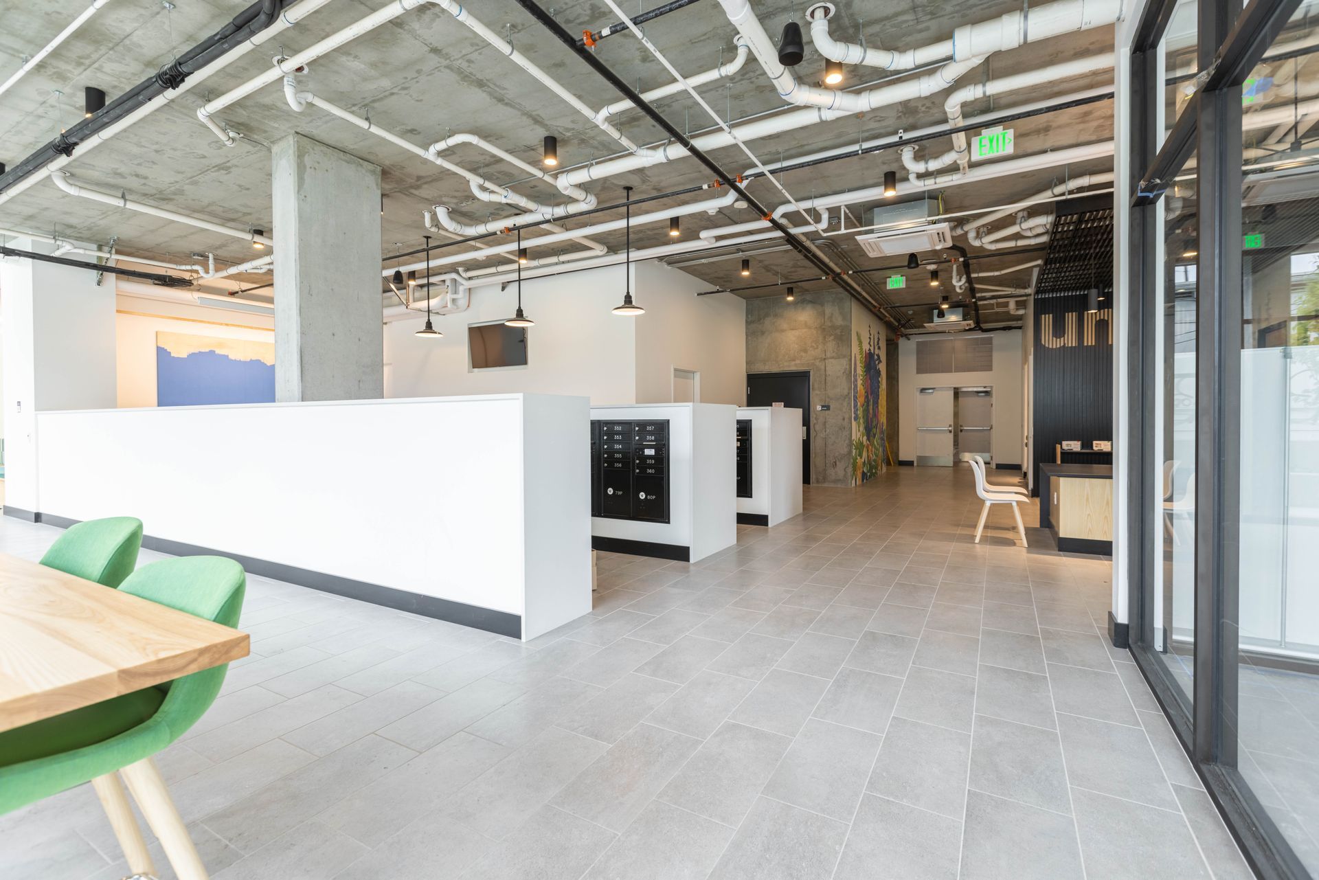 Modern open office lounge with white partitions, exposed ceiling, and glass walls