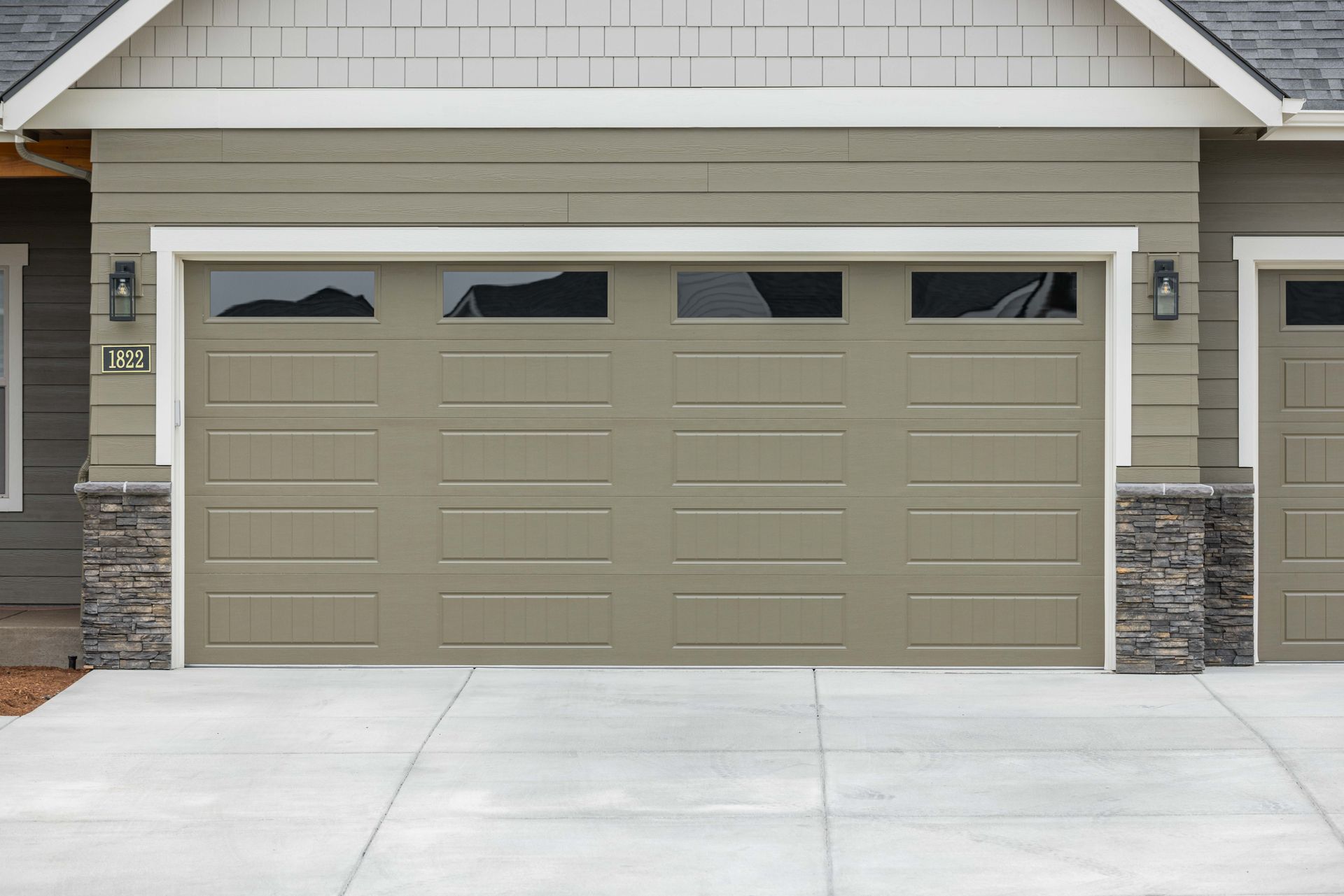 Modern two-car beige garage with stone accents and a concrete driveway