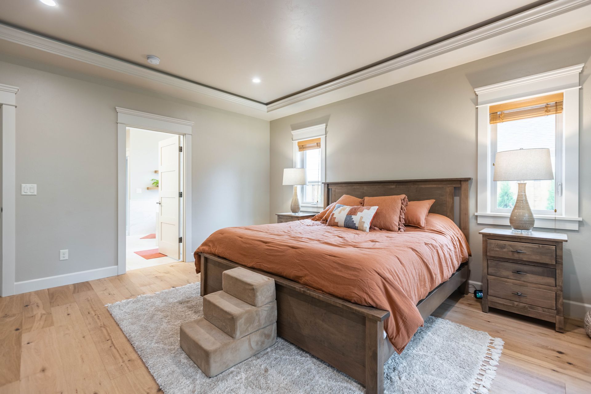 Spacious bedroom with a large bed, gray walls, white trim, and windows letting in natural light