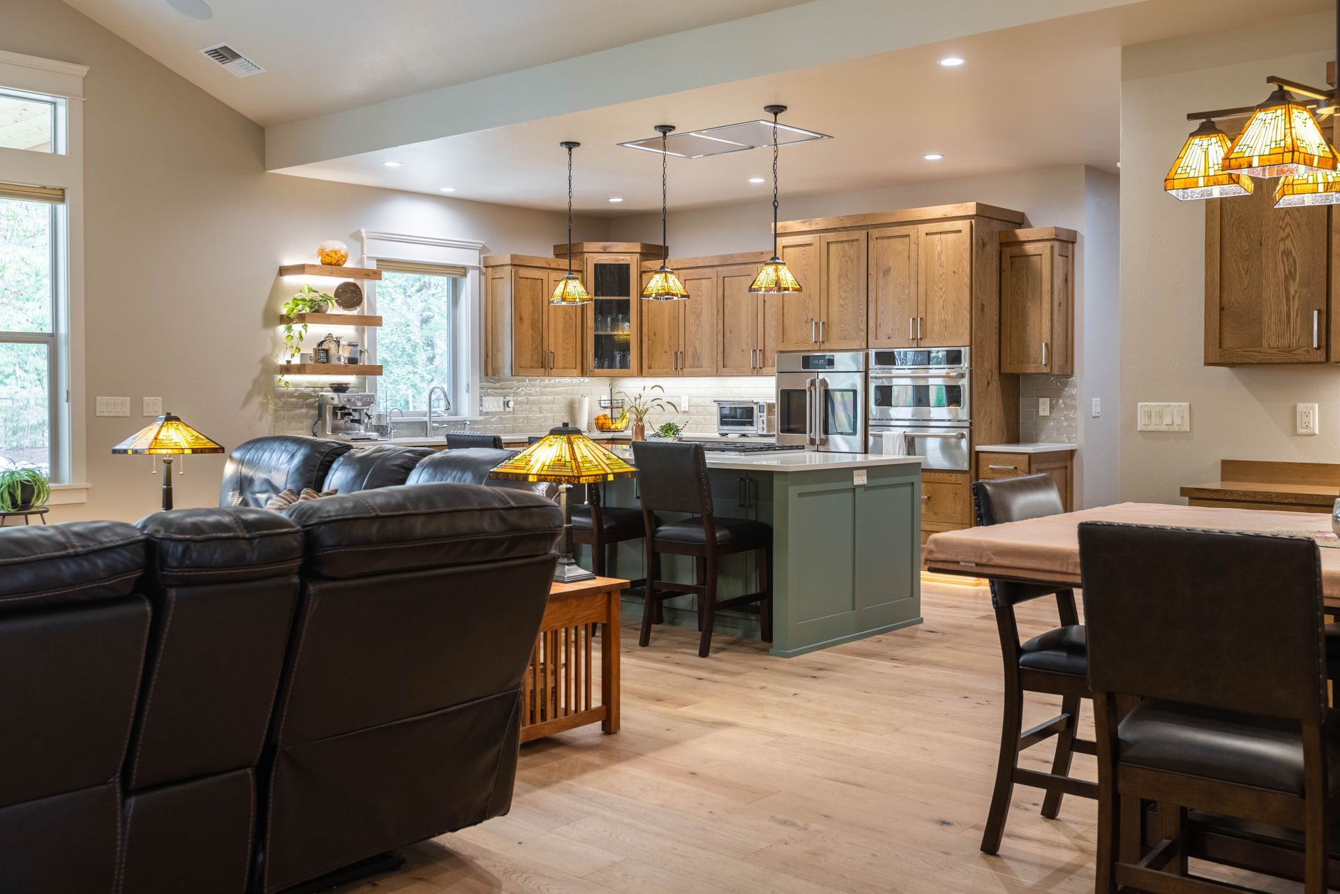 Open-concept kitchen and living room with wood cabinets, island, leather sofa, and dining table