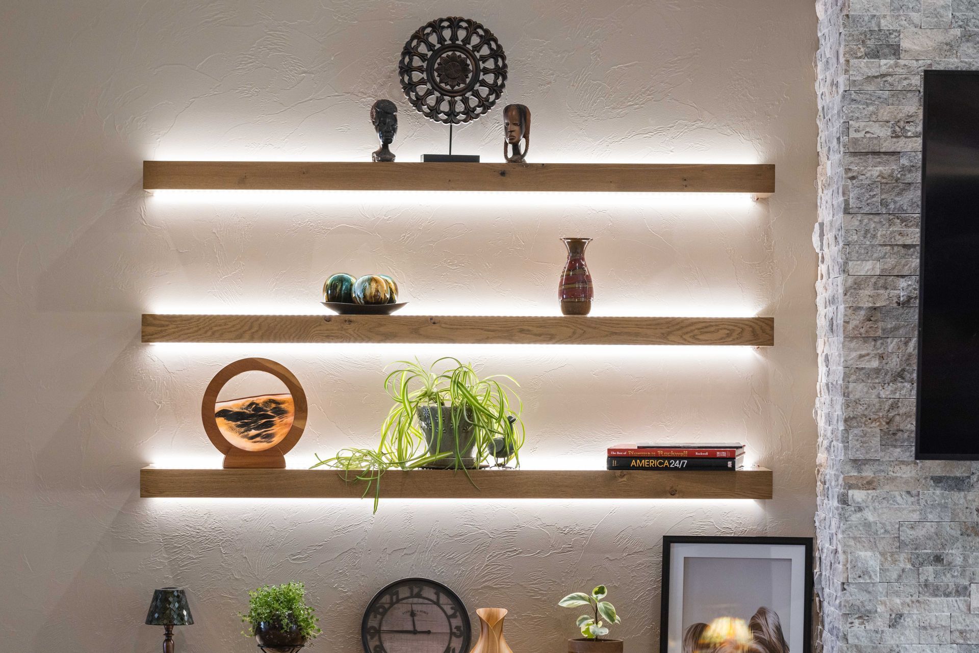 Backlit floating shelves with plants, decor, and framed art on a textured wall