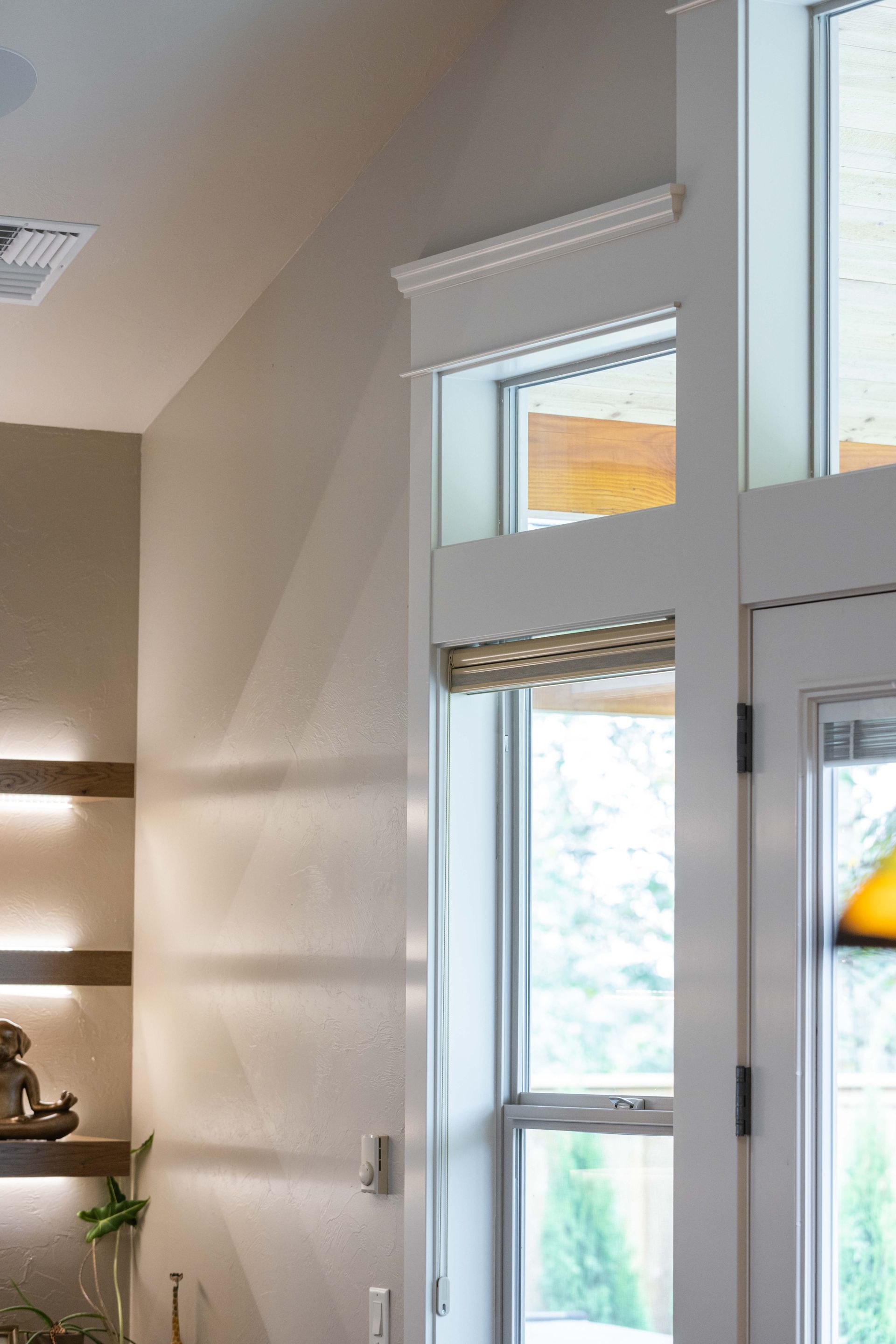 Bright entryway with tall windows and white trim, sunlight streaming into a beige interior.