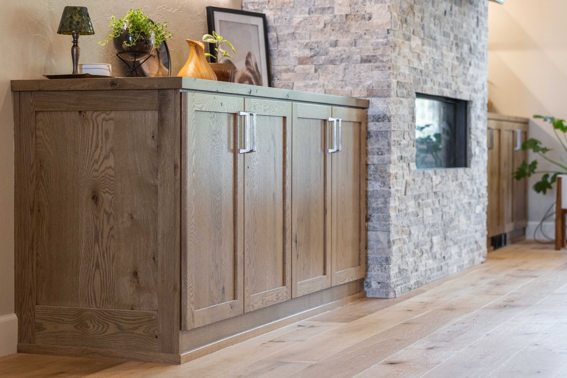 Wooden cabinet with decor in a modern hallway beside a stone wall and light wood floor