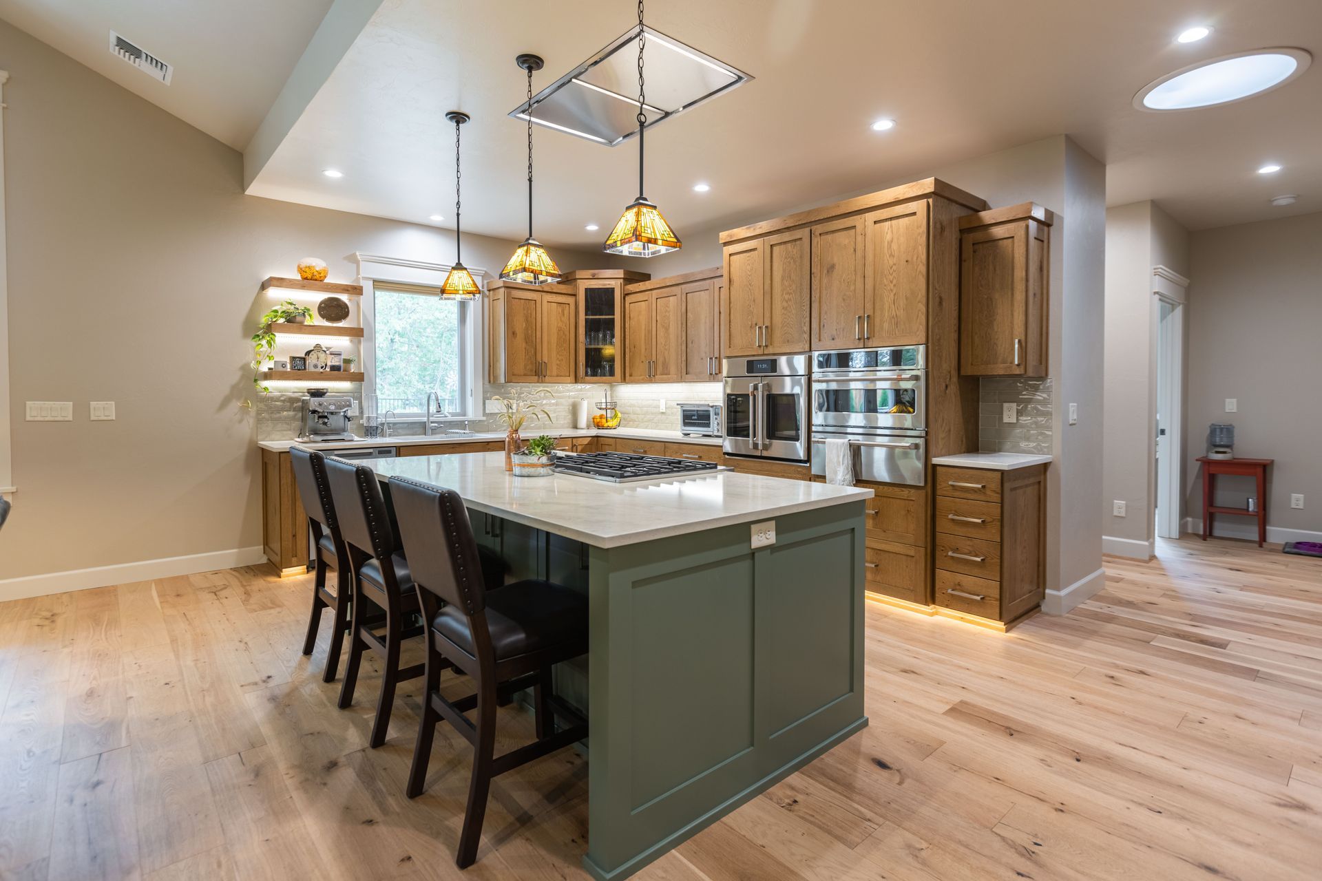 Modern kitchen with island, pendant lights, wood cabinets, stainless appliances, and hardwood floors