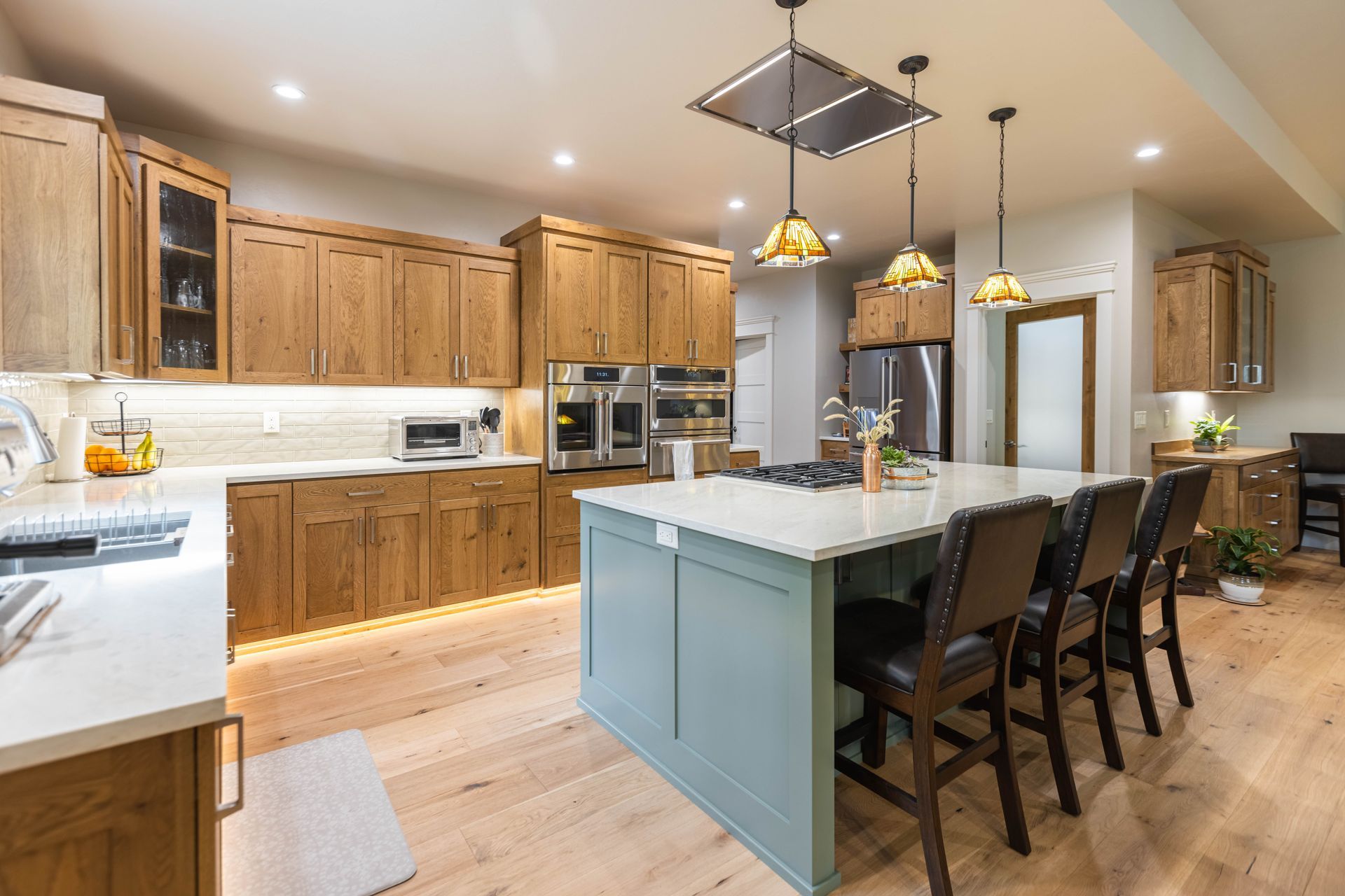 Bright modern kitchen with wood cabinets, island, pendant lights, and bar stools