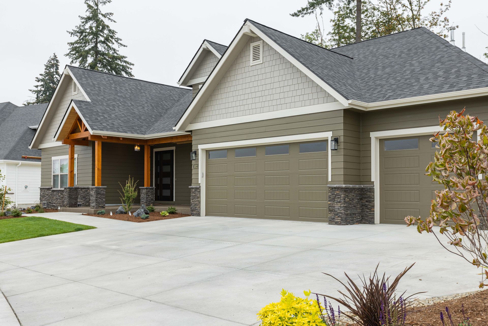 Modern suburban house with stone accents, gray roof, and three-car garage