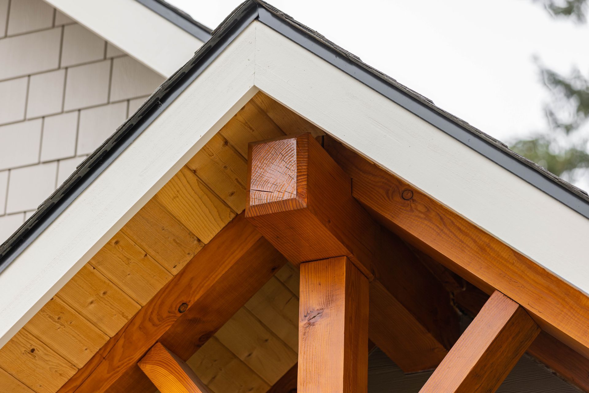Close-up of a wooden roof truss under a white gable roof with gray trim.