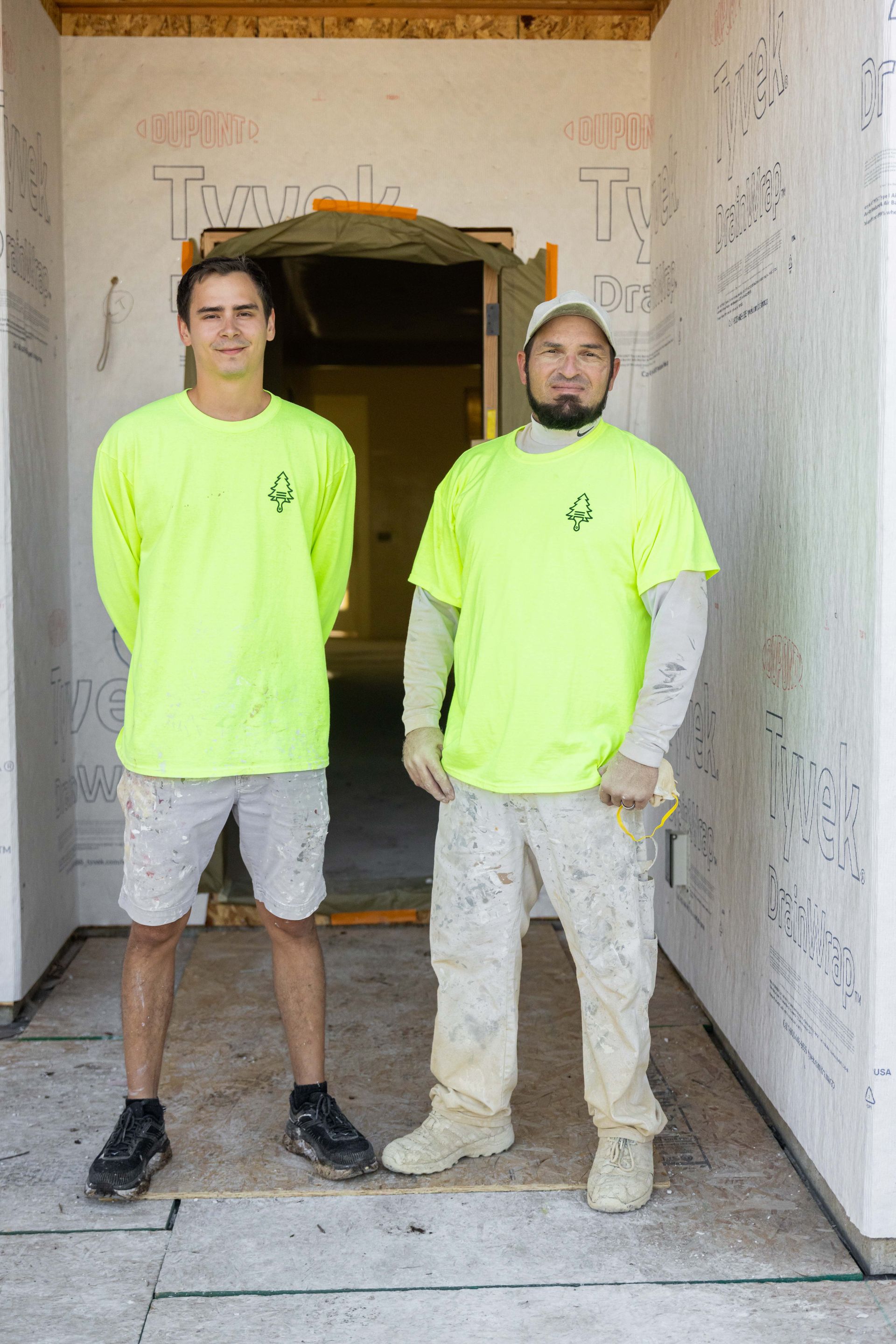 Two workers in neon yellow shirts standing in a building doorway on a construction site.