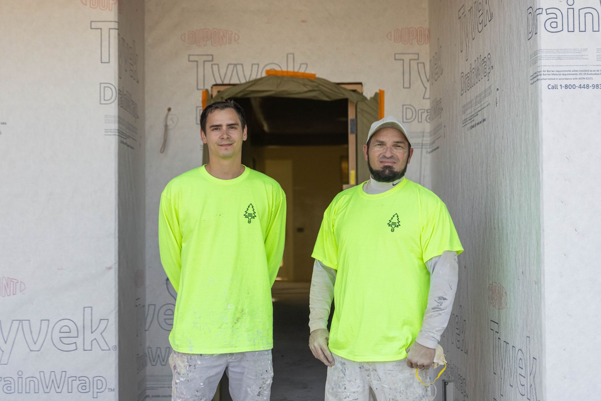 Two workers in neon yellow shirts standing in a construction doorway