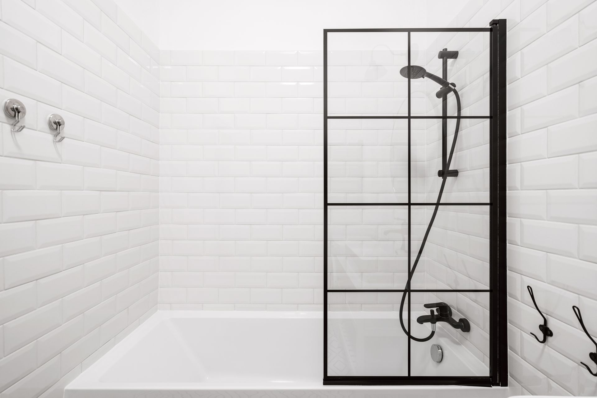 Minimal white bathroom with a bathtub and black-framed glass shower screen. Minimal white bathroom with a bathtub and black-framed glass shower screen.