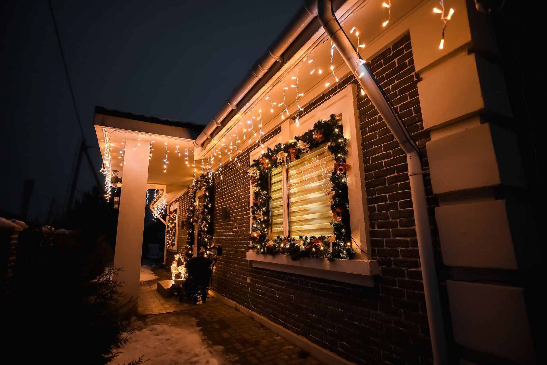 House exterior at night decorated with Christmas lights and garland.