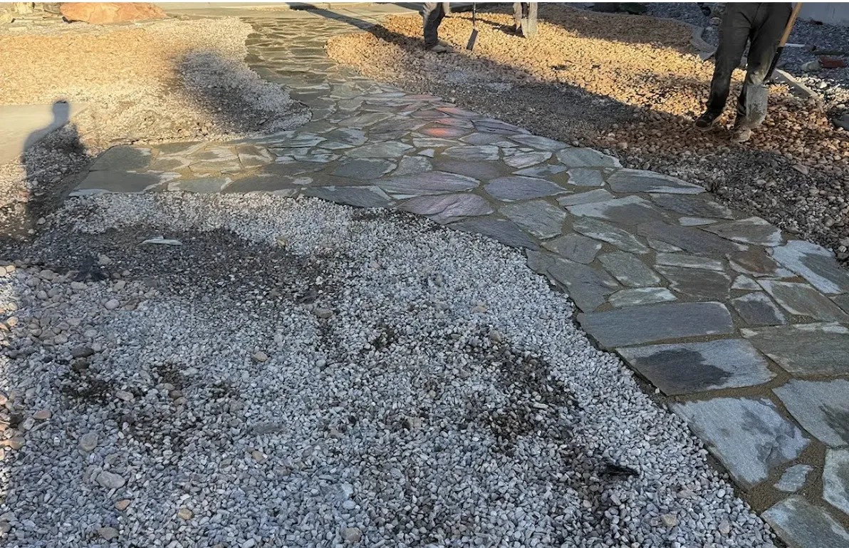 Pathway construction: flagstones set in concrete, surrounded by gravel. A person is standing nearby.
