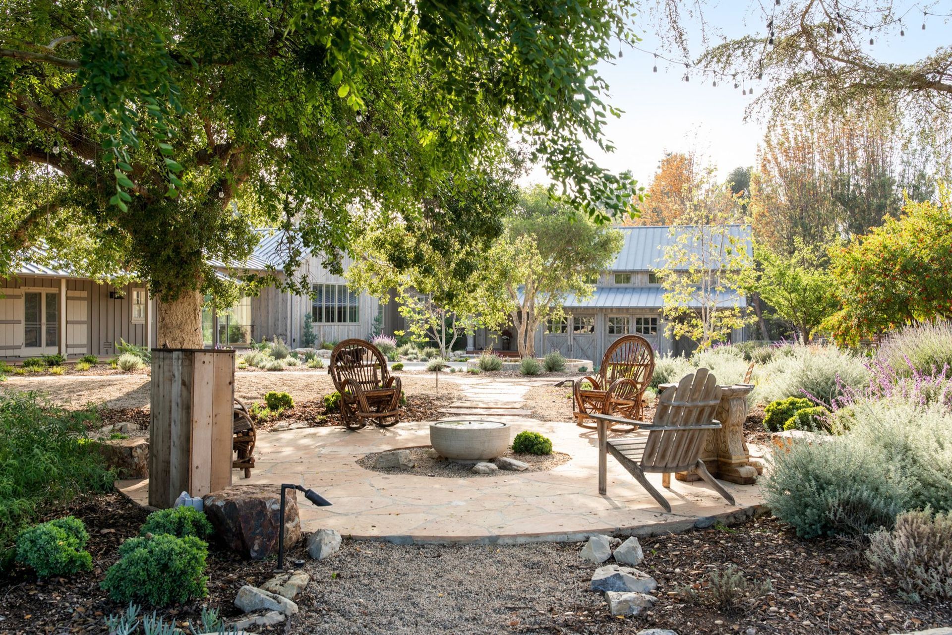 Outdoor seating area with chairs around a fire pit, next to a building and trees. Outdoor seating area with chairs around a fire pit, next to a building and trees.