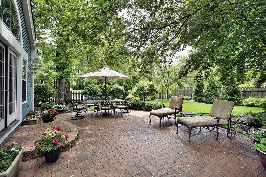 Patio with brick flooring, outdoor furniture, and lush greenery. Patio with brick flooring, outdoor furniture, and lush greenery.