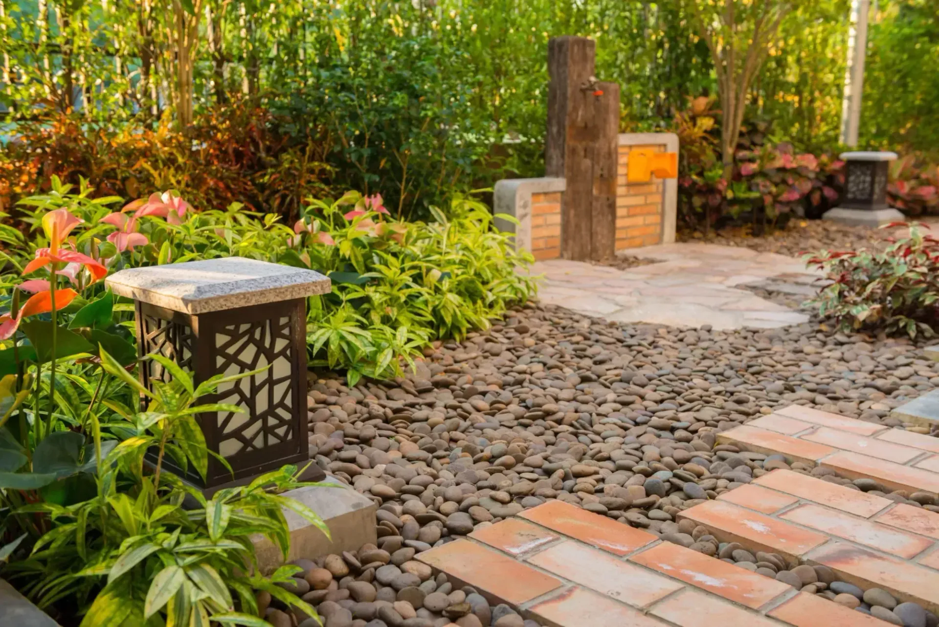 Garden pathway with brick steps, gravel, and diverse lush greenery.