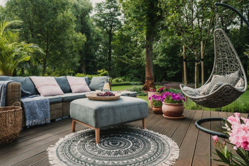 Outdoor patio with blue sofa, hanging chair, and plants in a lush garden setting. Outdoor patio with blue sofa, hanging chair, and plants in a lush garden setting.