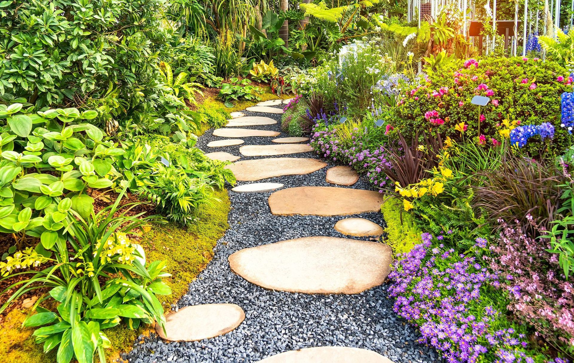 Stone path winds through a garden of colorful flowers and lush greenery. Stone path winds through a garden of colorful flowers and lush greenery.