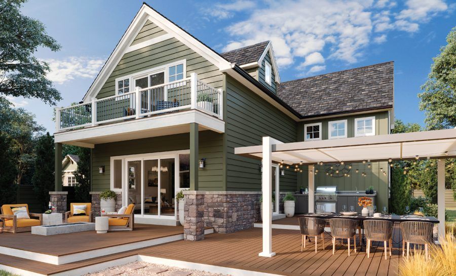 Two-story green house with a deck and outdoor kitchen. The house has a balcony. Sunny day.