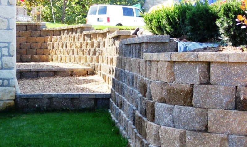Stone retaining walls with steps leading up, in a yard with green grass and a van in the background. Stone retaining walls with steps leading up, in a yard with green grass and a van in the background.