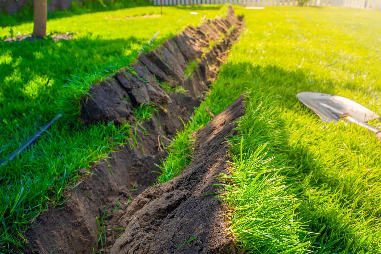 A trench dug in green grass, with a shovel nearby, on a sunny day. A trench dug in green grass, with a shovel nearby, on a sunny day.