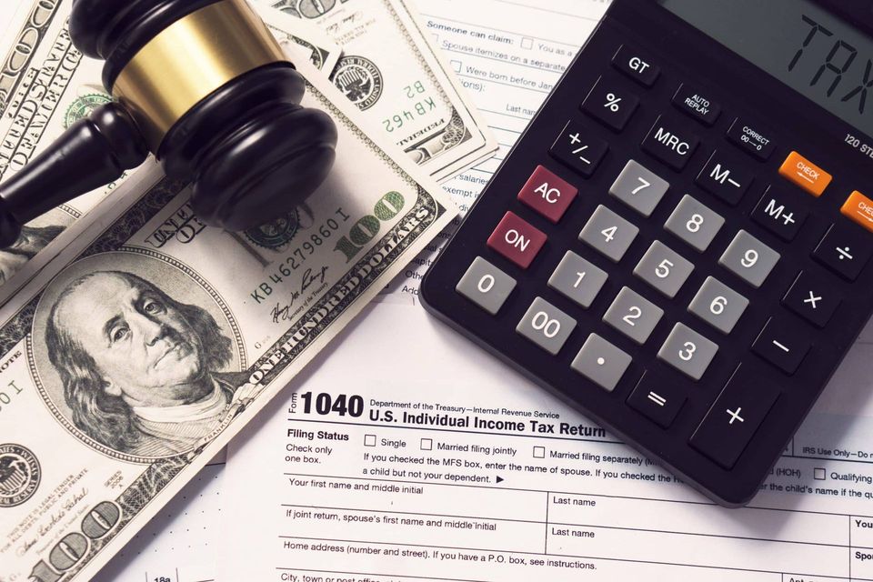 Tax forms, calculator, gavel, and U.S. dollar bills on a desk