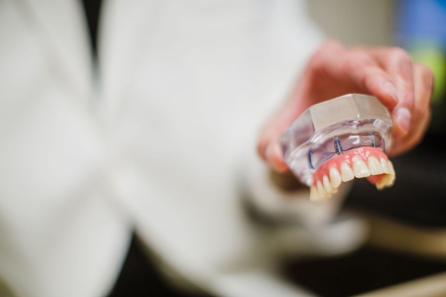 Dr. Aaron Miller holds a clear dental model with pink gums and white teeth