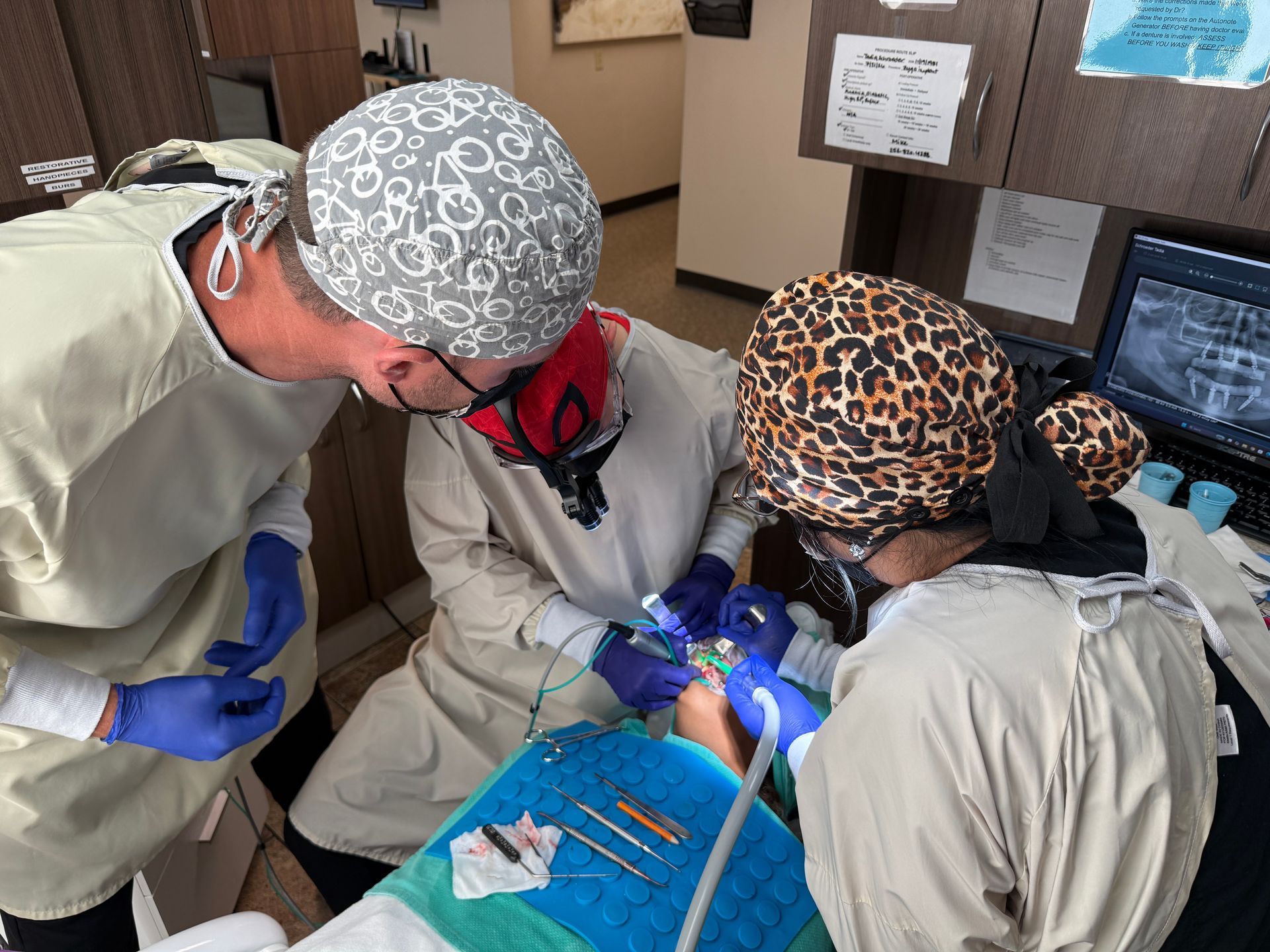 Dr. Aaron Miller mentors a surgeon and their assistant while they operate over a patient.
