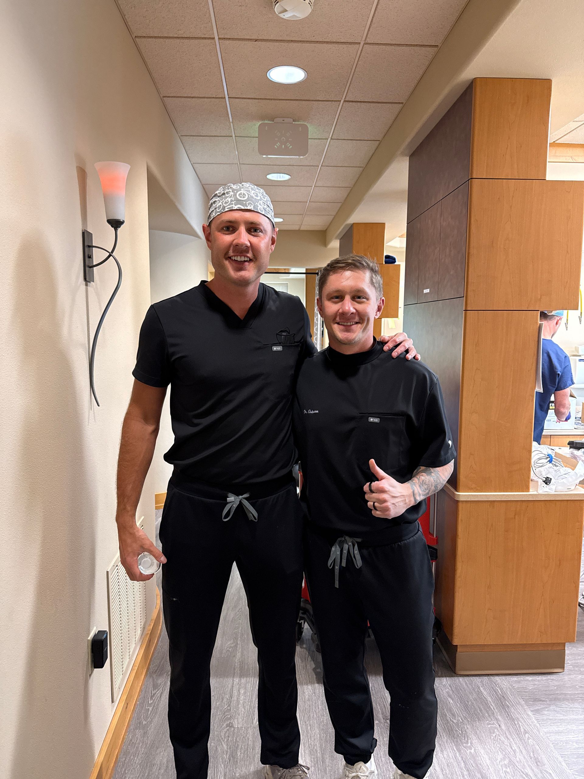 Dr. Aaron Miller and another dentist in black scrubs smile in a clinic