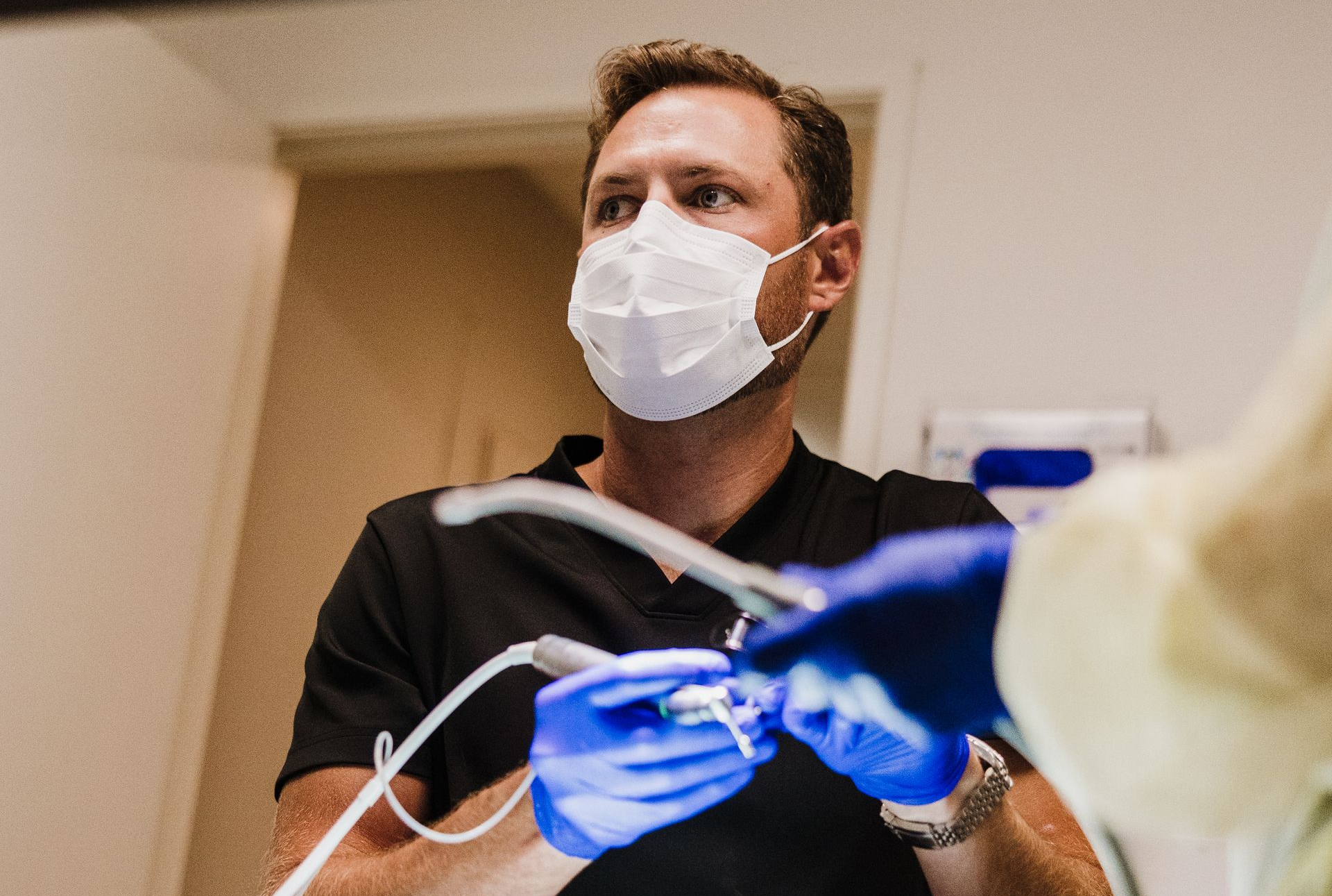 Dr. Aaron Miller holding dental tools while working with a patient in a clinic