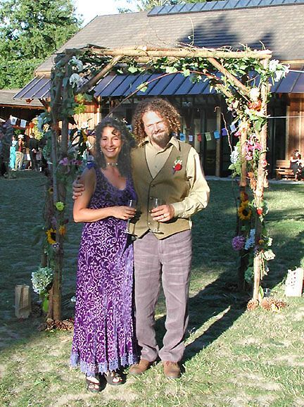 Deborah and Frank beneath their flower and greenery covered wedding arch