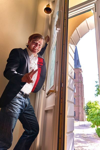 A man in a suit is standing in a doorway giving a peace sign