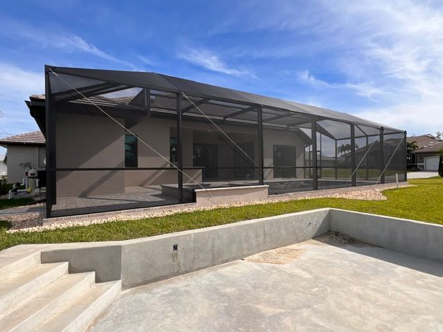 Modern house with a screened patio and concrete steps beside a landscaped yard