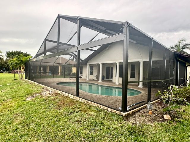 Screened patio enclosing a rectangular swimming pool beside a modern white house