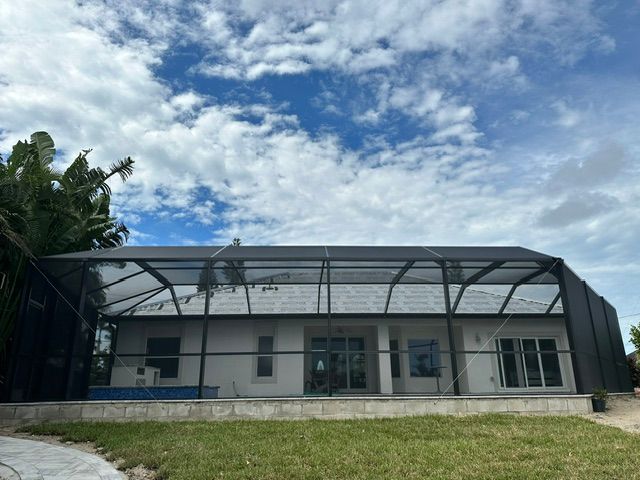 Modern single-story building with a covered metal frame, white walls, and large windows under a cloudy sky