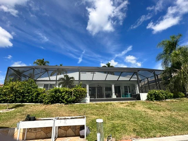 Modern house with a screened porch, lawn, and bright blue sky