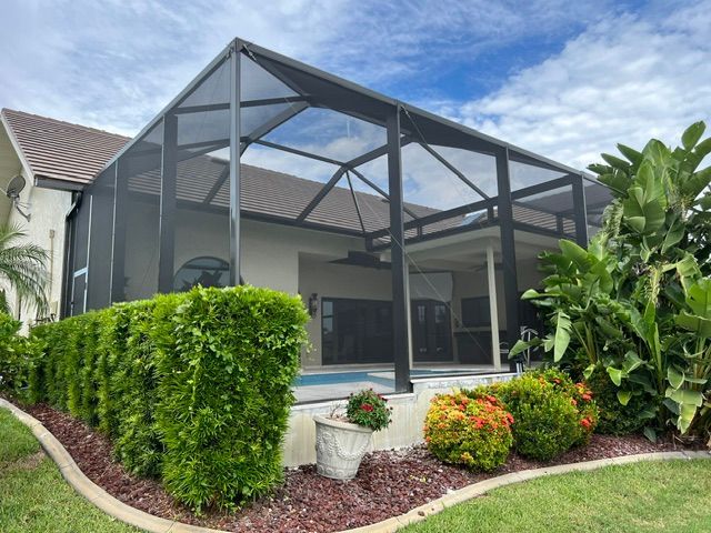 Screened patio enclosure beside a landscaped garden and suburban home