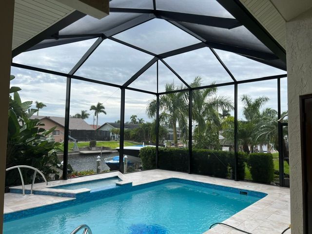 Screened backyard pool with patio and palm trees under a covered lanai