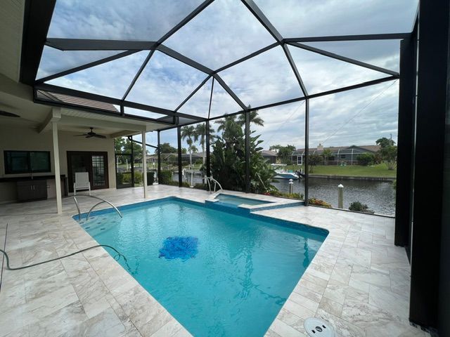 Screened-in patio with a turquoise pool and lake view under a geometric roof
