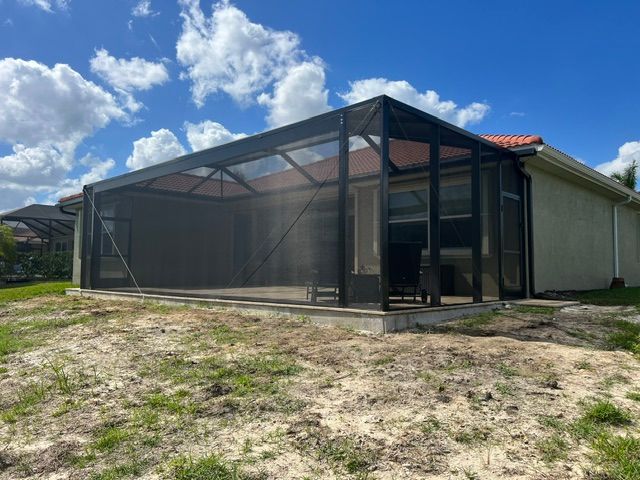 Screened patio enclosure attached to a house on a sunny day