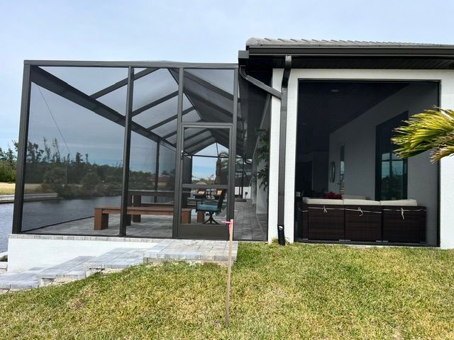 Modern house patio with screened enclosure beside a lawn and water view
