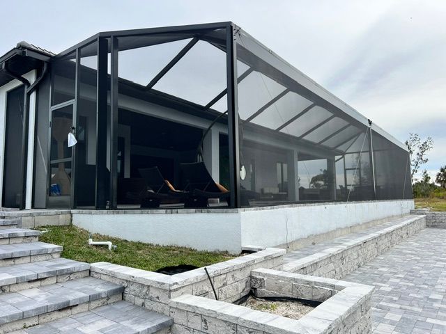 Modern glass-walled house with a screened patio and stone steps in a landscaped yard