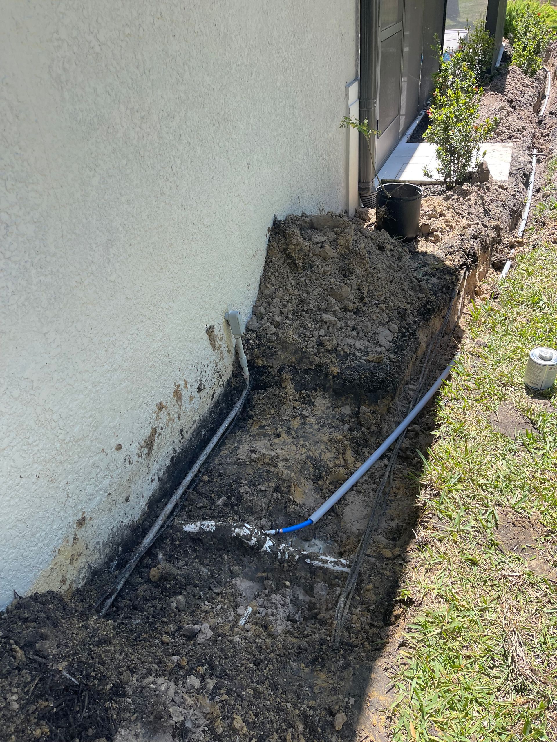 A pipe is being installed in the dirt next to a house.
