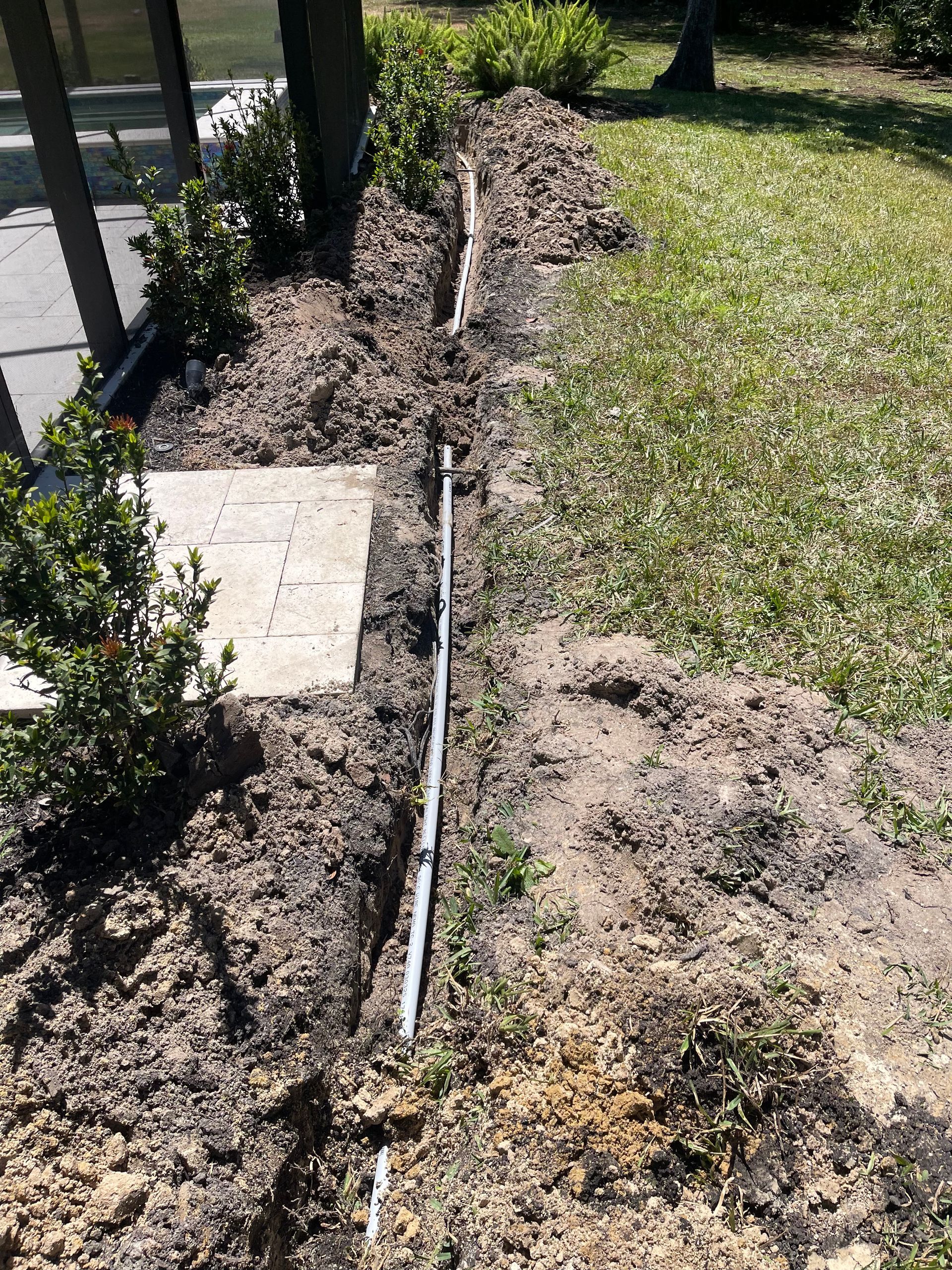 A pipe is laying in the dirt in a yard.